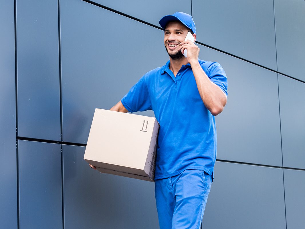 delivery man with cardboard box talking by phone